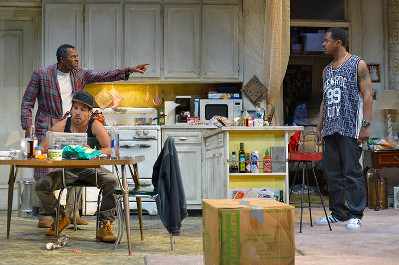 Walter “Pops” Washington (Carl Lumbly, left) argues with his son, Junior (Samuel Ray Gates, right), while Oswaldo (Lakin Valdez, center) reads the newspaper in Stephen Adly Guirgis’s Pulitzer Prize–winning dark comedy, 
